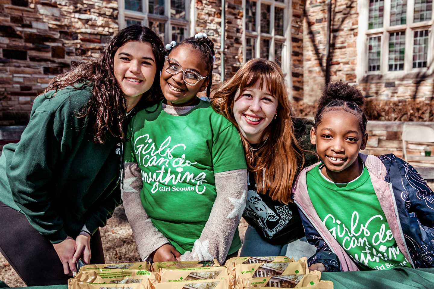 Two college women with two young girl scouts smiling
