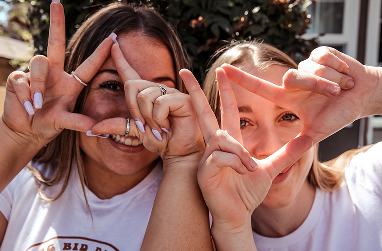 Two collegiate members throwing Kappa Delta Hands